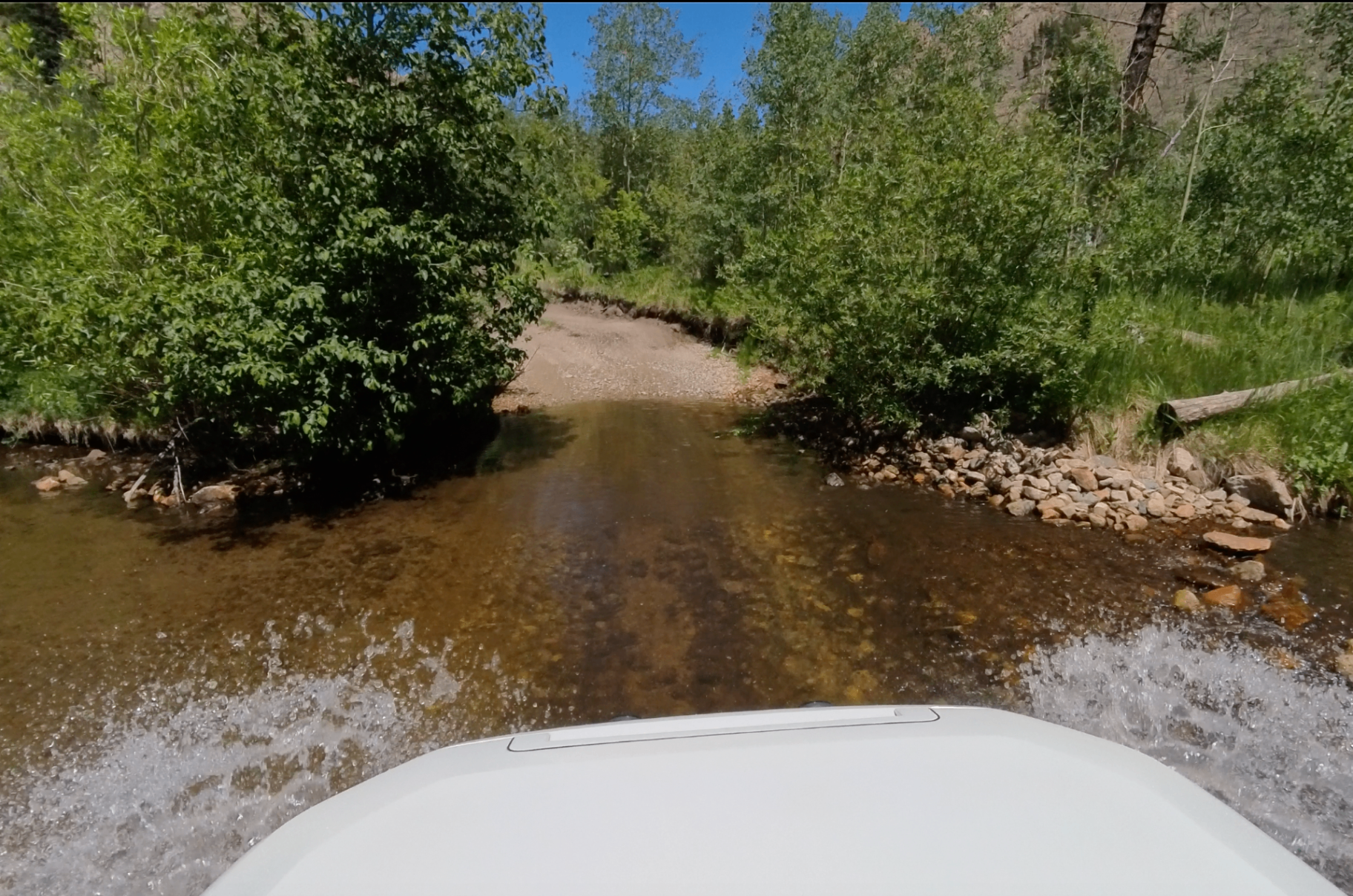 Crossing a shallow mountain creek with water splashing around the hood on Medano Pass.